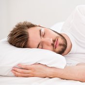 Eschscholtzia et sommeil : un jeune homme avec une barbe dormant dans un lit blanc